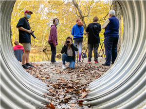 looking through a tunnel at students photographing the river